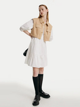 a lady in white mini dress with suede vest and black loafers